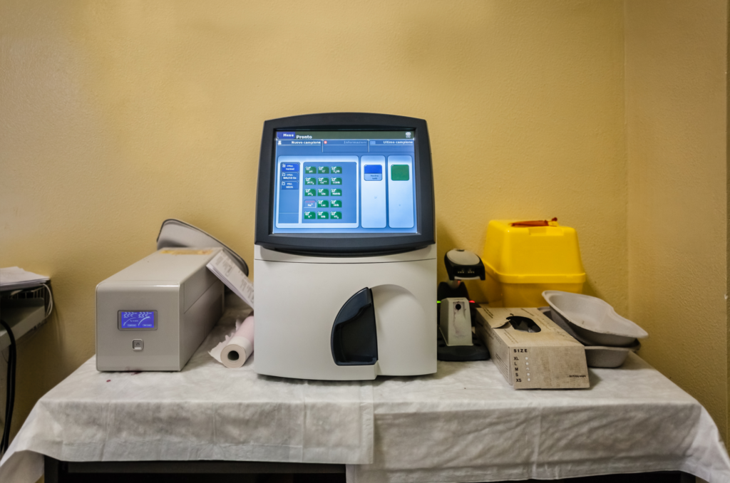 A modern medical laboratory setup with various equipment on a table against a yellow wall.