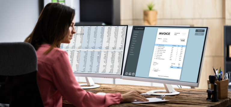 A laboratory technician is working on a computer with dual monitors in an office. The left monitor displays a spreadsheet with laboratory data, while the right monitor shows an invoice being prepared using laboratory management software.