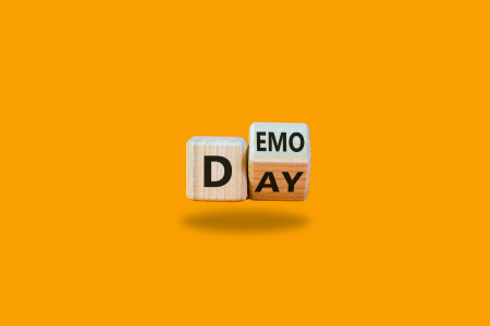 demo-commemoration “Wooden letter blocks spelling ‘D DEMO’ on an orange background.”